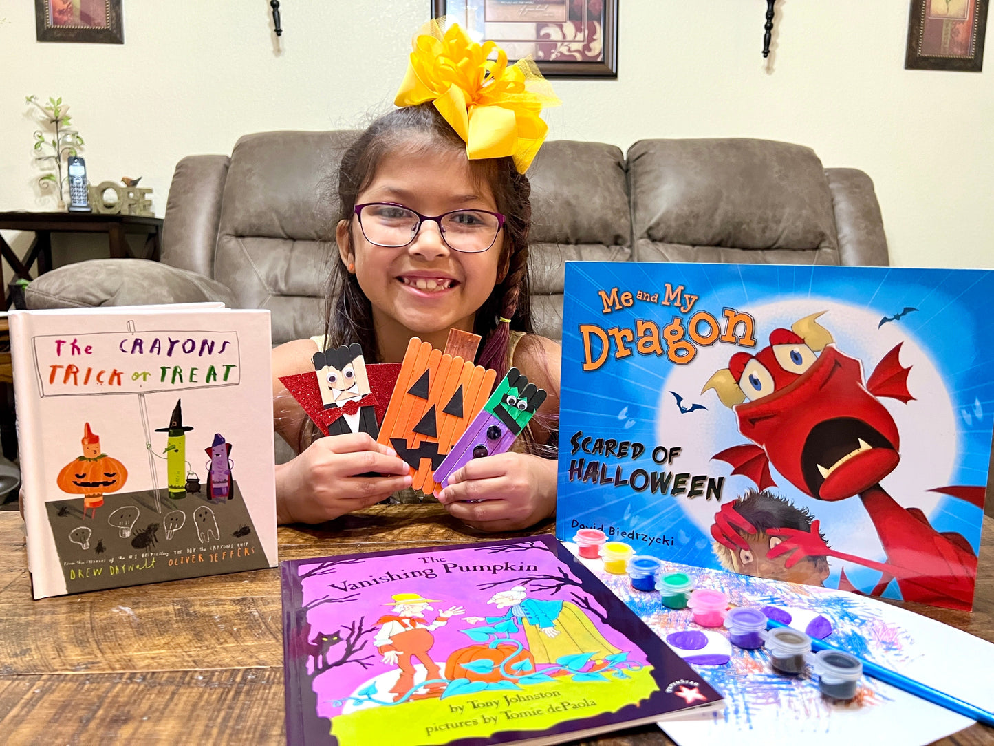 happy child customer showing her books and finished crafts from the halloween themed literacy box