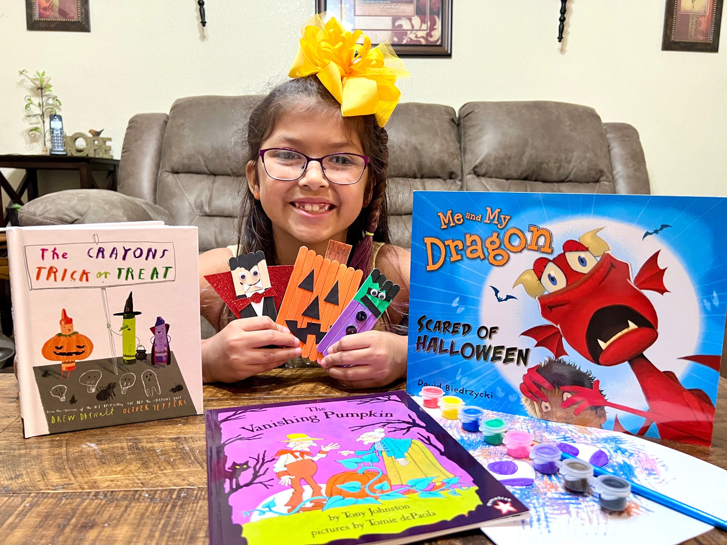 happy child customer showing her books and finished crafts from the halloween themed literacy box